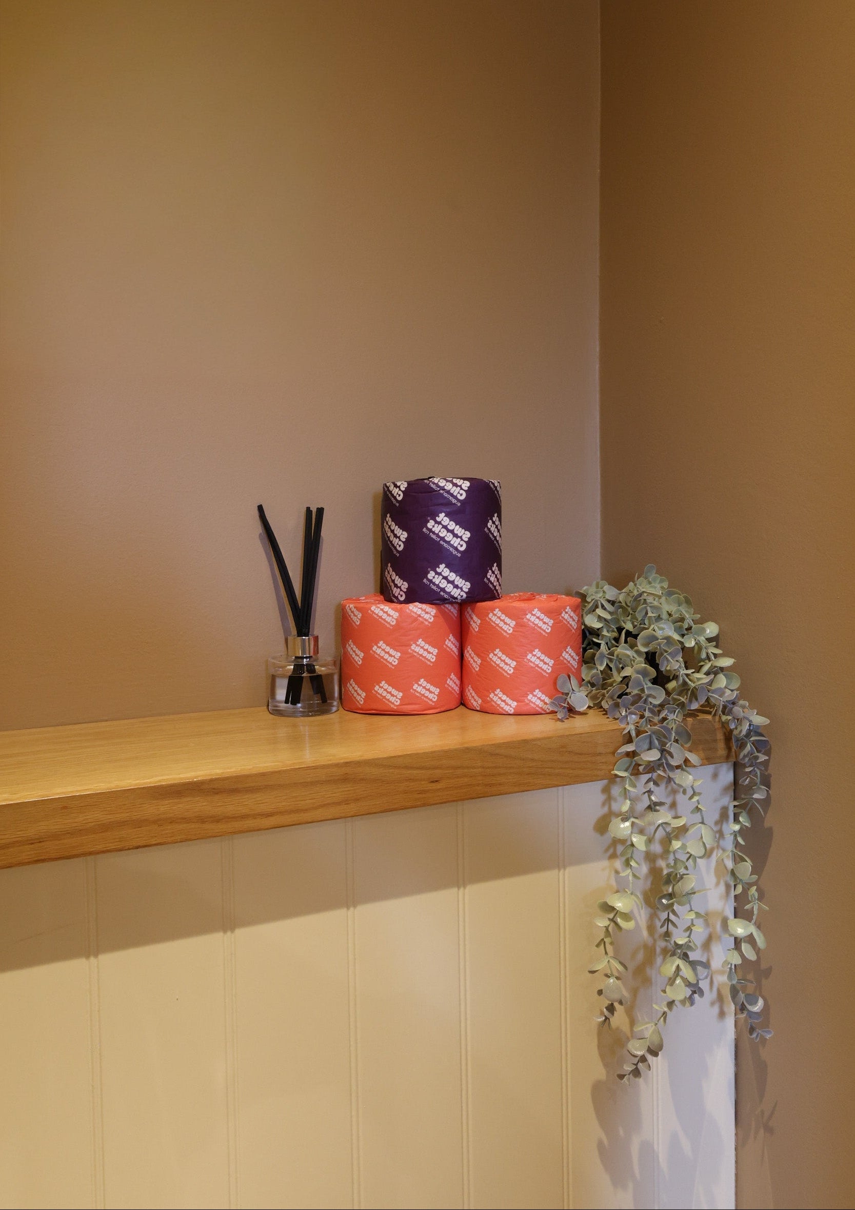 Sugarcane toilet rolls stacked on a washroom shelf beside a plant