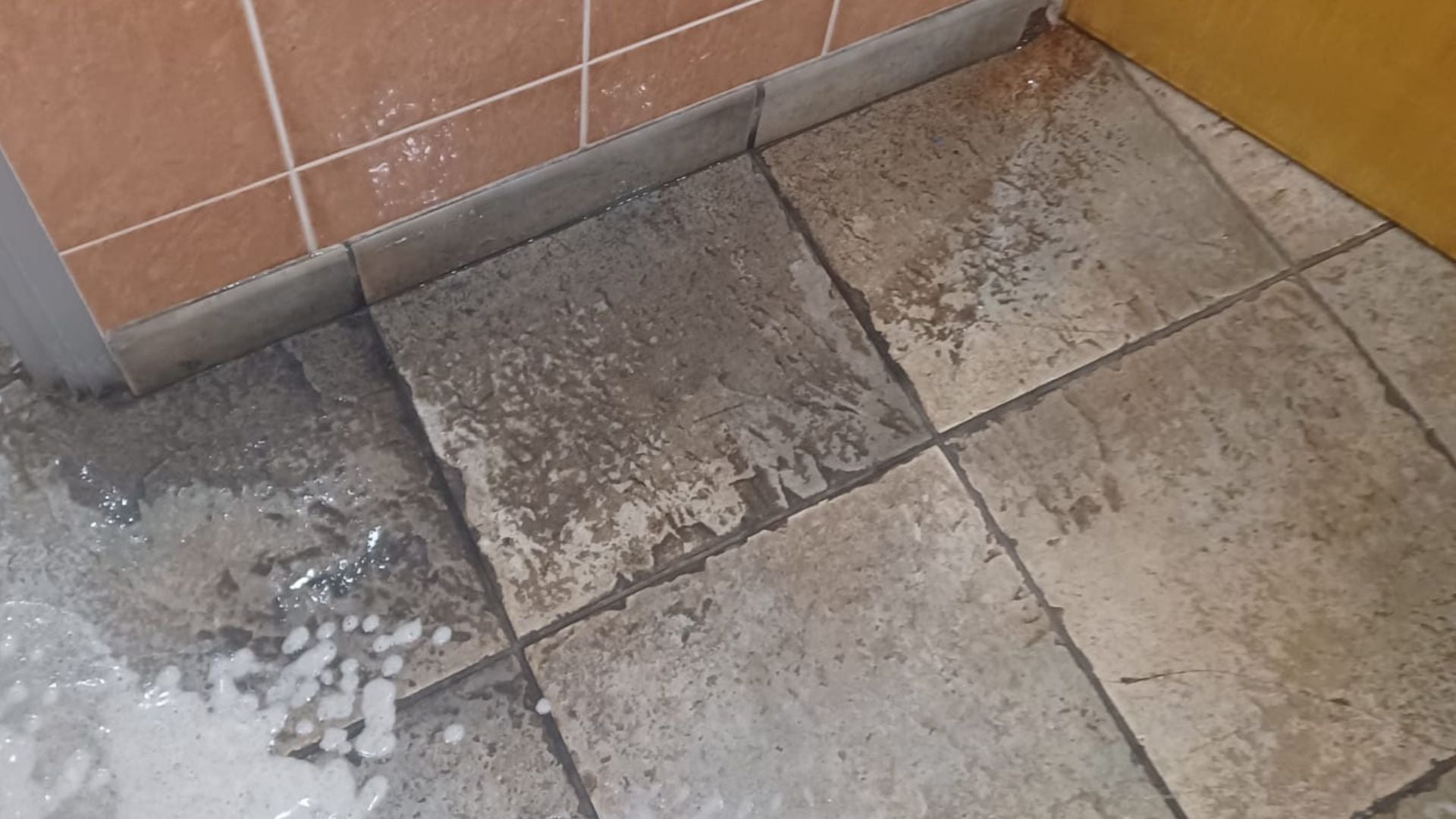 Washroom floor before a deep clean, showing built-up residue