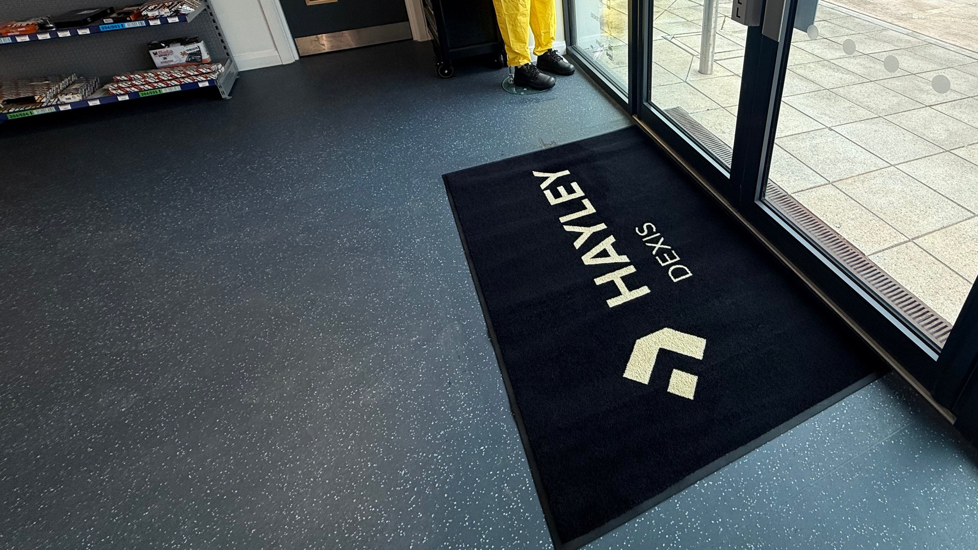 Logo mats: branded black entrance mat at a building doorway