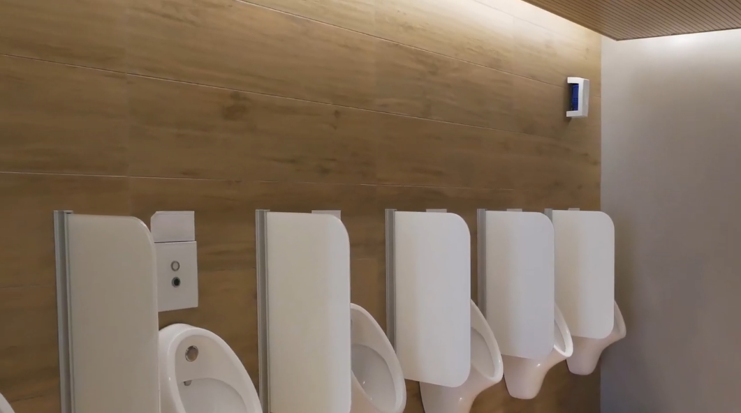 Non-aerosol airfresh dispenser in white above a row of urinals