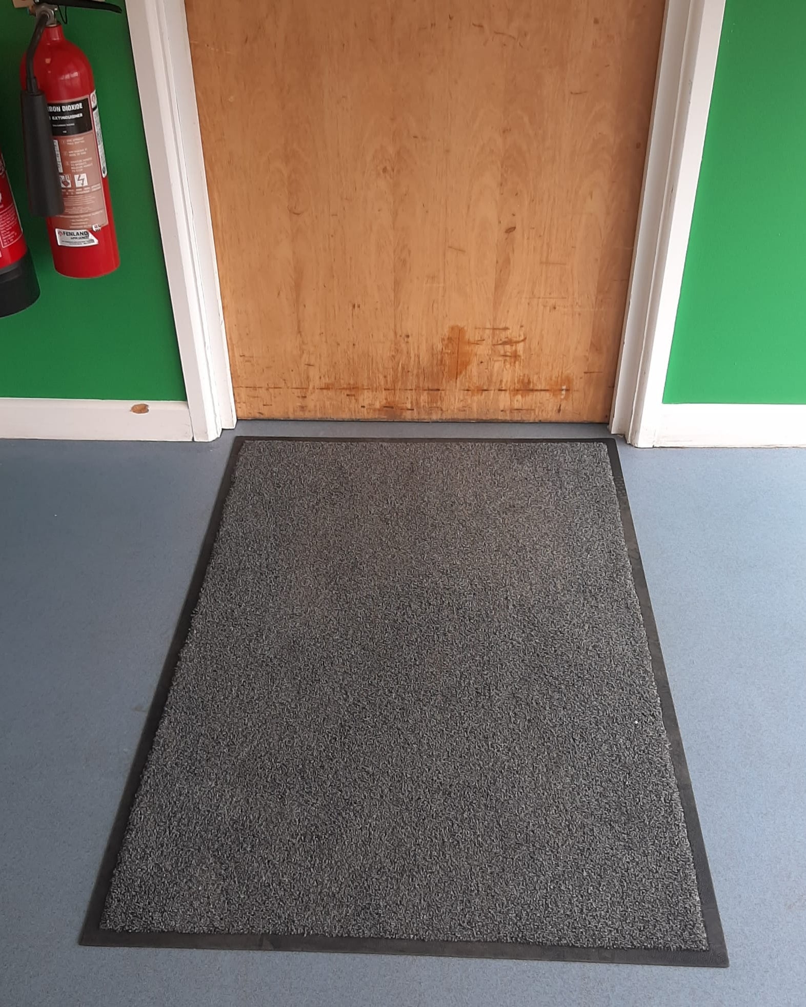 Emmanuel College Cambridge traffic mat fitted infront of a door in grey