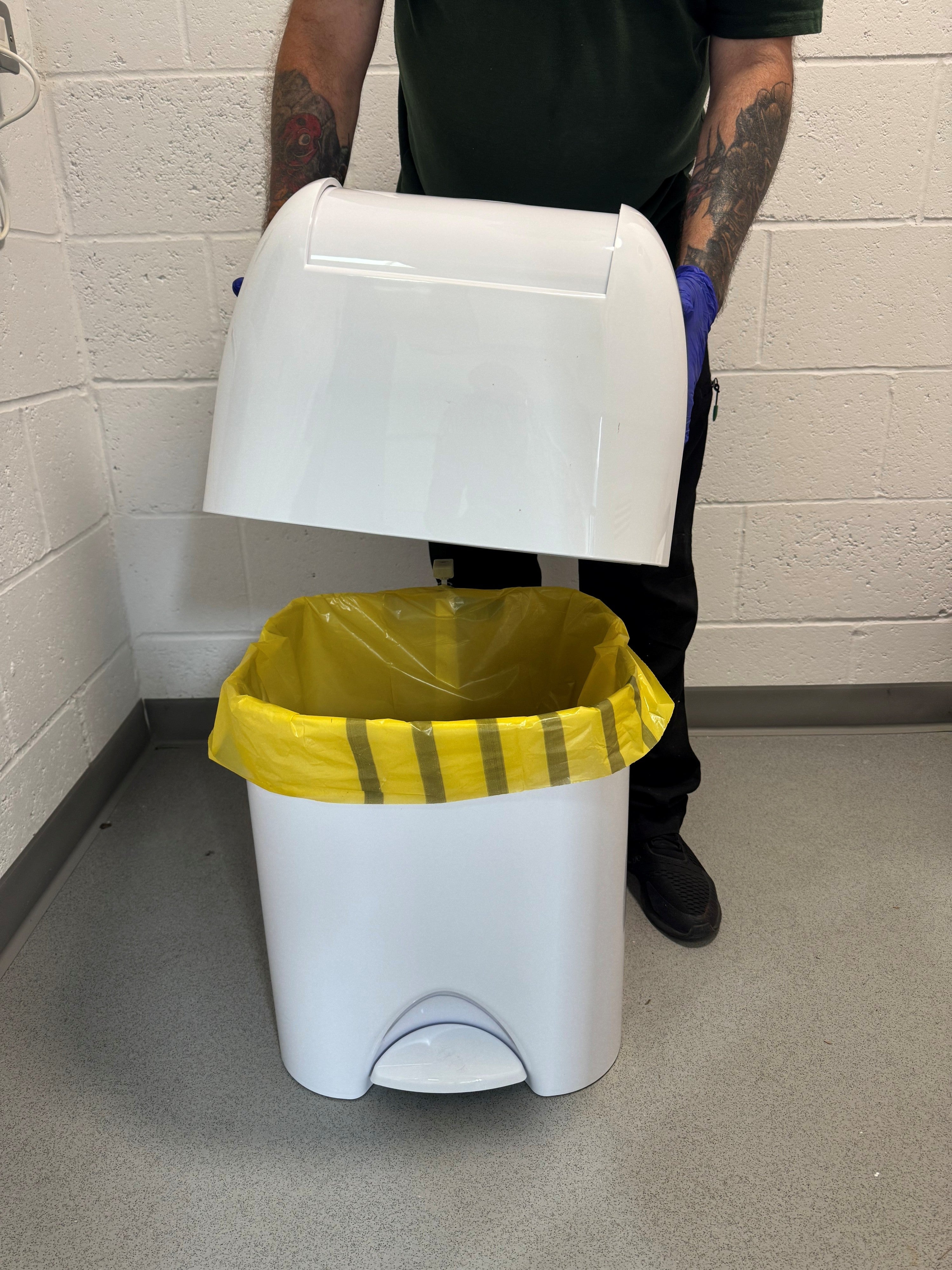 Offensive waste disposal: engineer holding a white medical disposal unit with a tiger offensive waste bag