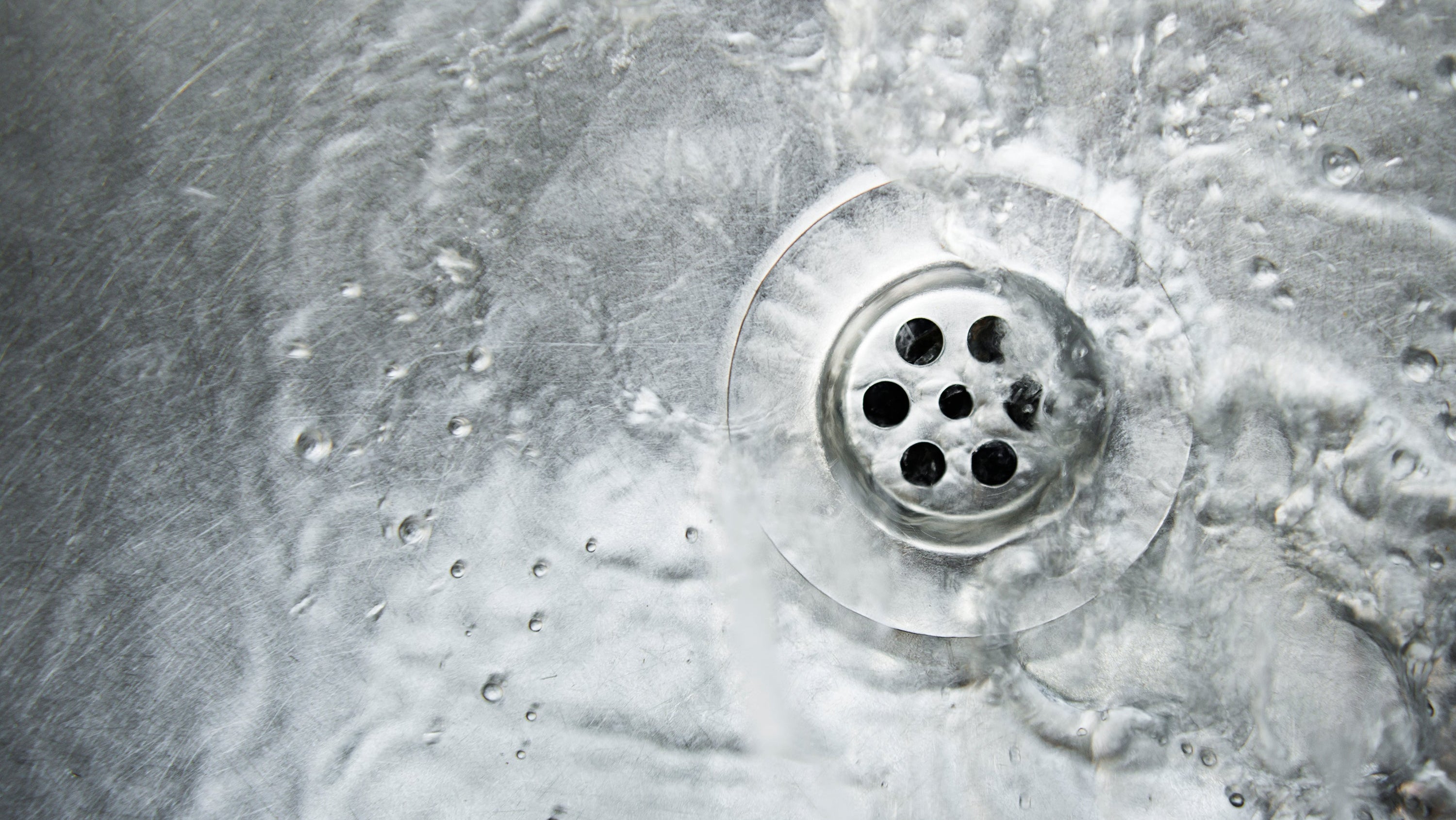 Sink deep clean: water running over a polished stainless steel sink