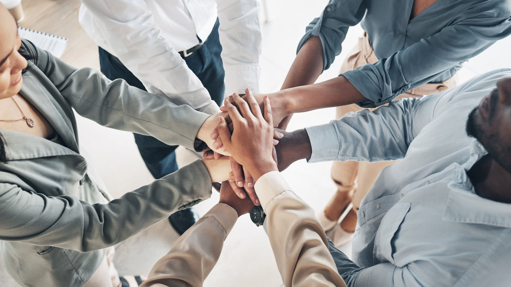 Business team joining hands, reflecting a people-first culture