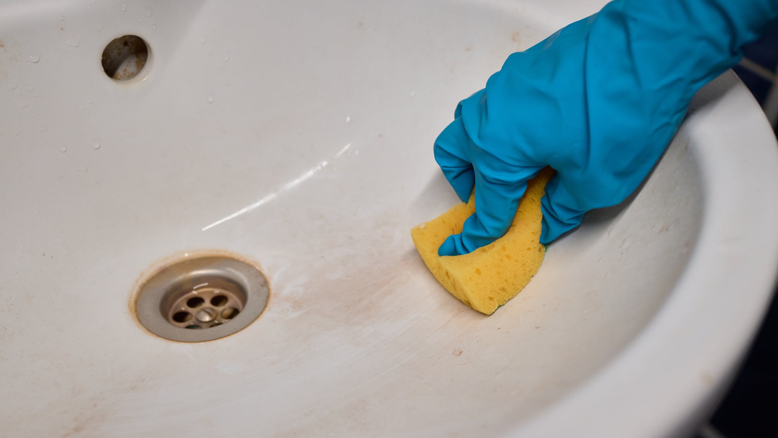Sink deep clean: a sink being cleaned with a sponge