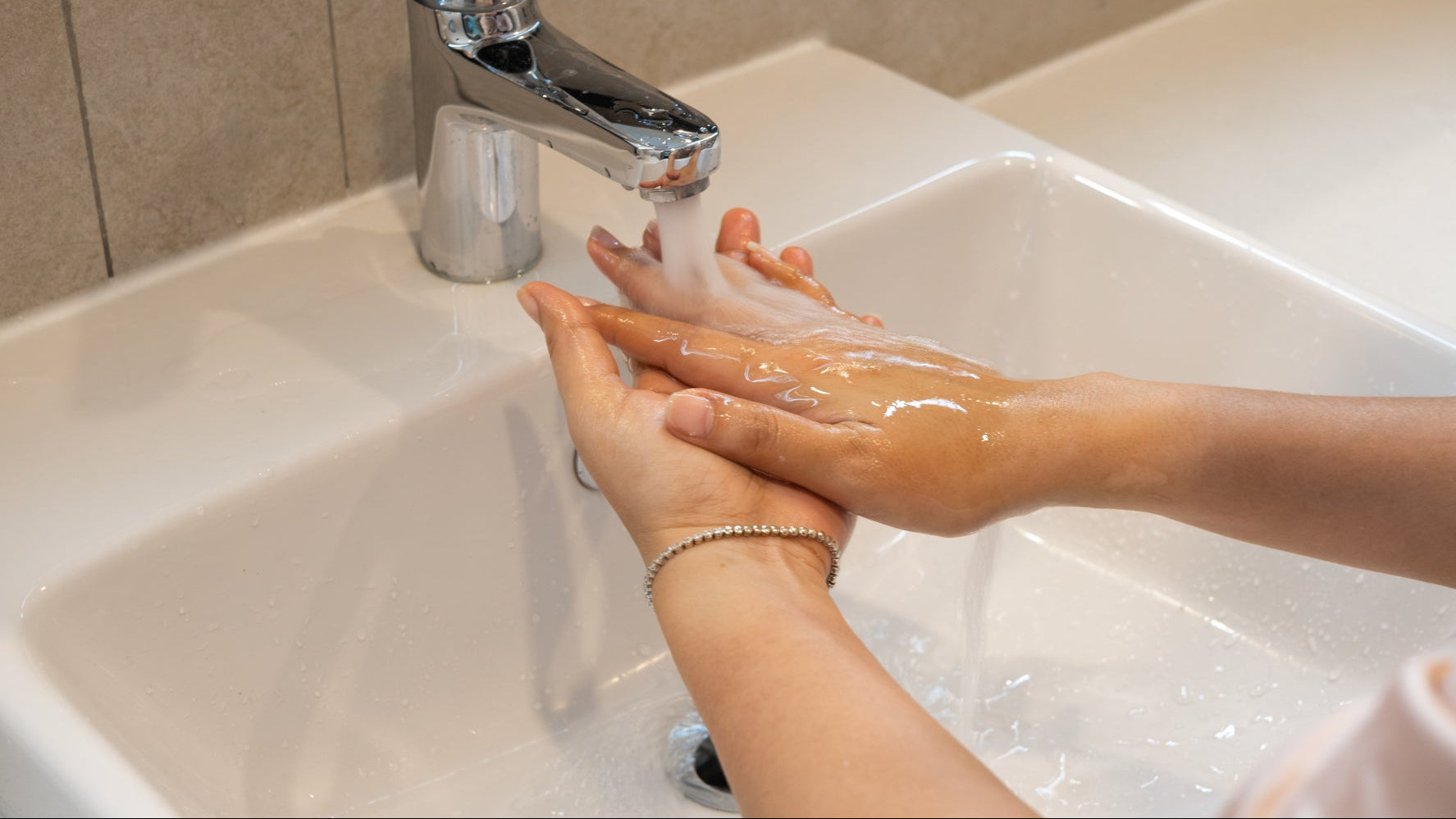 Hand washing with soap under a running tap in a washroom