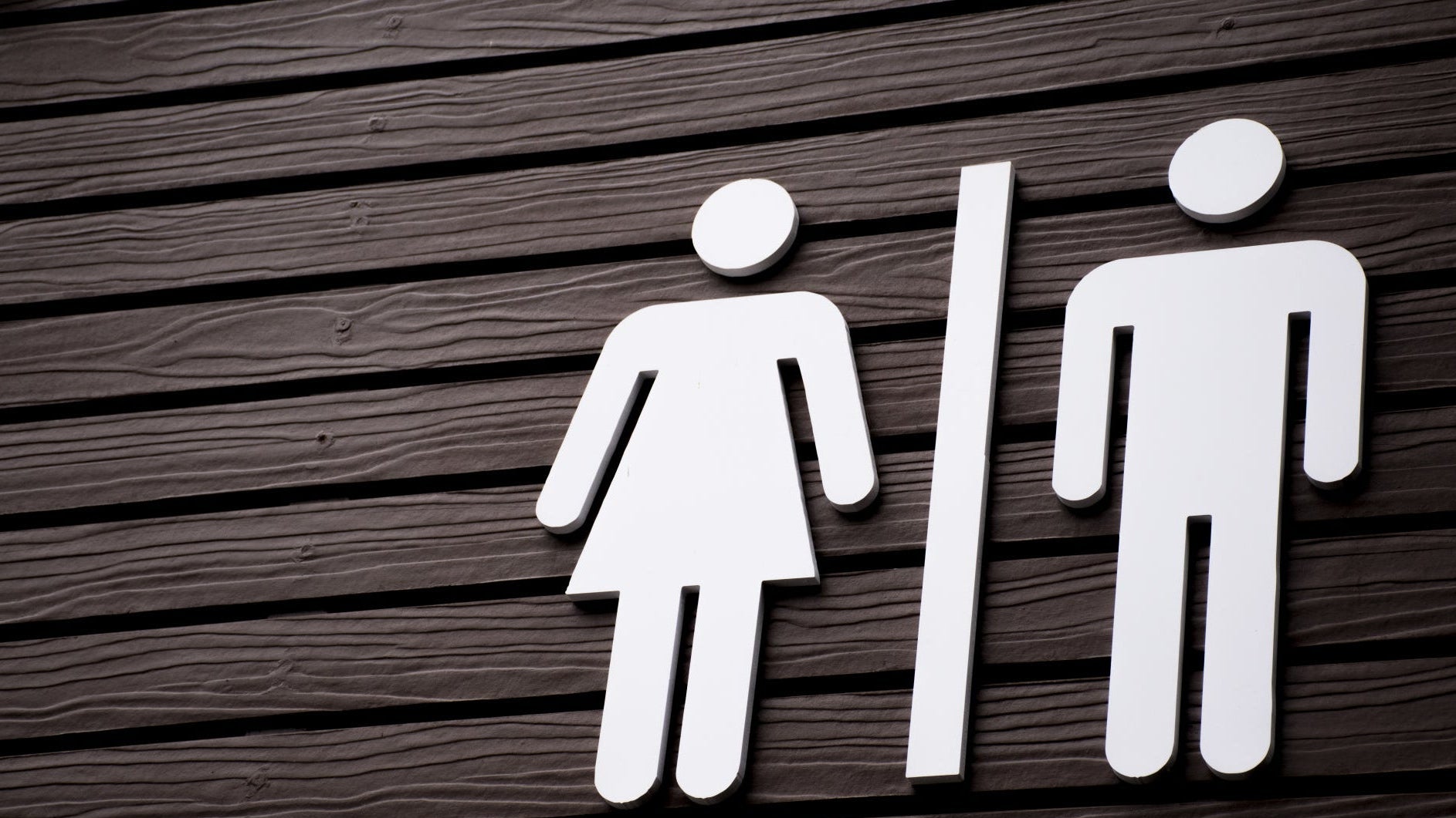 Washroom signage on a wooden door in a public building